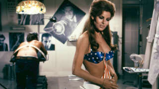 Raquel Welch wearing stars and stripes bikini with gunbelt as Roger Herron is strapped to table in a scene from the 1970 movie Myra Breckinridge. (Photo by Screen Archives/Getty Images)