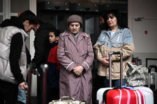 Ukrainian refugees stand next to their belongings after they arrive from Moldova at the international airport of Bordeaux in Merignac on April 21, 2022. - A first charter with 71 Ukrainian refugees on board landed in Bordeaux from Moldova, a country bordering Ukraine that Paris has pledged to help by transferring 2,500 displaced people to France. (Photo by Philippe LOPEZ / AFP)