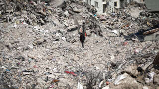 A man walks atop the rubble of collapsed buildings in Kahramanmaras, southeastern Turkey, on February 18, 2023. - A 7.8-magnitude earthquake hit near Gaziantep, Turkey, in the early hours of February 6, followed by another 7.5-magnitude tremor just after midday. The quakes caused widespread destruction in southern Turkey and northern Syria and has killed more than 44,000 people. (Photo by Zein Al RIFAI / AFP)