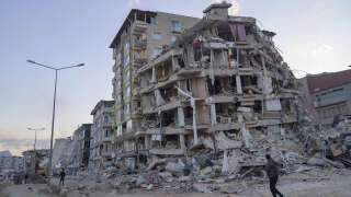 A man looks up at a collapsed building in Hatay, southern Turkey on February 19, 2023. - A  7.8-magnitude earthquake hit near Gaziantep, Turkey, in the early hours of February 6, followed by another 7.5-magnitude tremor just after midday. The quakes caused widespread destruction in southern Turkey and northern Syria and has killed more than 40,000 people. (Photo by Yasin AKGUL / AFP)