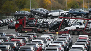 A truck driver carries cars on the Sochaux Stellantis car plant parking in Sochaux, eastern France, on November 25, 2022. - Due to a lack of truck drivers, the Stellantis plant of Sochaux is not able to export all its cars and has to stock them on the Lure-Malbouhans desaffected airport, about 40 km from the industrial site. (Photo by SEBASTIEN BOZON / AFP)