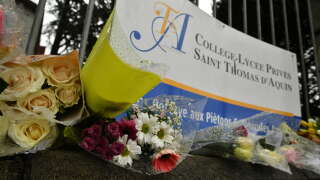 People place bouquets of flowers at the entrance gate of the Saint-Thomas d’Aquin middle school where a teacher died after being stabbed by a student, in Saint-Jean-de-Luz, southwestern France, on February 23, 2023. - A teacher at a school in southwest France was killed on February 22, in a stabbing attack by a teenage pupil during her class, the regional prosecutor said. The teacher, in her 50s, was teaching a class at the school in the seaside town of Saint-Jean-de-Luz when the pupil attacked her with a knife. (Photo by GAIZKA IROZ / AFP)