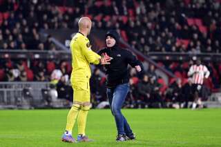 A pitch invader (R) attempts an assault on Sevilla FC goalkeeper Marko Dmitrovic (L) during the UEFA Europa league play-off match between PSV Eindhoven and Sevilla FC at the Phillips stadium in Eindhoven on February 23, 2023. (Photo by Olaf Kraak / ANP / AFP) / Netherlands OUT