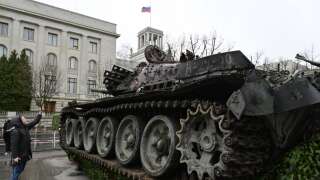 A woman takes a picture of a Russian T-72 tank destroyed in Ukraine placed in front of Russia's embassy in Berlin on February 24, 2023, on the first anniversary of the invasion of Ukraine. - The wrecked tank was placed as an art installation by the 