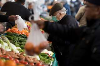 A man wearing a facemask for protective measures, choses fruits and vegetables at the Barbes market, on March 18, 2020 in Paris as a strict lockdown came into in effect in France to stop the spread of COVID-19, caused by the novel coronavirus. - A strict lockdown requiring most people in France to remain at home came into effect at midday on March 17, 2020, prohibiting all but essential outings in a bid to curb the coronavirus spread. The government has said tens of thousands of police will be patrolling streets and issuing fines of 135 euros ($150) for people without a written declaration justifying their reasons for being out (Photo by JOEL SAGET / AFP)