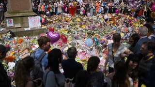 (FILES) In this file photo taken on May 25, 2017 People stop by a mass of flowers to observe a minute's silence in St Ann's Square in Manchester, northwest England, as a mark of respect to the victims of the May 22 terror attack at the Manchester Arena. - The Manchester bomber who killed 22 people at an Ariana Grande concert in 2017 might have been stopped if Britain's MI5 security service had acted on vital intelligence, an official inquiry found on March 2, 2023. Delays in relation to one of two pieces of intelligence led to the 