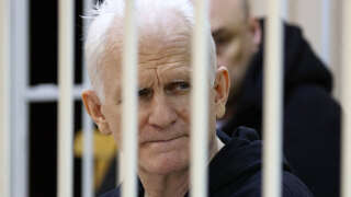 (FILES) In this file photo taken on January 05, 2023 Nobel Prize winner Ales Bialiatski is seen in the defendants' cage in the courtroom at the start of the hearing in Minsk. - A court in Belarus on March 3, 2023 sentenced Nobel Prize winner Ales Bialiatski to 10 years in prison, in a case his supporters see as punishment for his human rights work. The Viasna rights group founded by Bialiatski said in a statement that the 60-year-old had been convicted of smuggling and financing 