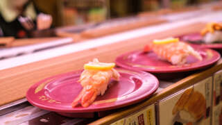 This picture shows plates of sushi on a conveyor belt at a sushi chain restaurant in Tokyo on February 3, 2023. (Photo by Philip FONG / AFP)