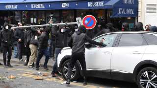 Protesters use a hammer and a street sign as they smash up the car of a on-duty doctor providing home visits in the area, on the sidelines of a demonstration in Paris on March 7, 2023, during a nationwide day of strikes and protests called by unions over the government's proposed pensions reform. - Fuel deliveries and public transport were severely disrupted in France on March 7 as unions kicked off a fresh day of protest against a pensions reform that would push back the retirement age for millions. Unions have vowed to bring the country to a standstill with strikes over the proposed changes, which include raising the minimum retirement age to 64 from 62 and increasing the number of years people have to make contributions for a full pension. (Photo by Alain JOCARD / AFP)