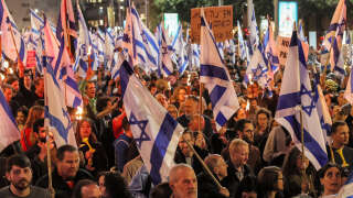 Demonstrators march with torches and with Israeli national flags during a protest against the government's controversial judicial reform bill in Tel Aviv on March 9, 2023. (Photo by JACK GUEZ / AFP)