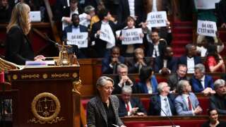 Members of Parliament of left-wing coalition NUPES (New People's Ecologic and Social Union) hold placards as France's Prime Minister Elisabeth Borne (C) arrives to confirm to force through pension law without parliament vote during a session on the government's pension reform at the lower house National Assembly, in Paris on March 16, 2023. - French President forced through pension law without parliament vote, after he  won approval from the upper house Senate for his reform of the pension system, which has sparked massive protests and strikes since the start of the year. (Photo by Alain JOCARD / AFP)