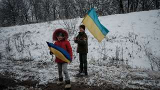 Children hold Ukrainian flags along the road near Sloviansk on January 30, 2023, amid the Russian invasion of Ukraine. (Photo by YASUYOSHI CHIBA / AFP)