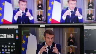 French President Emmanuel Macron is seen on screens as he speaks during a TV interview from the Elysee Palace, in Paris, on March 22, 2023. - French President is to make on March 22, 2023 his first public comments on the crisis sparked by his government forcing through a pensions overhaul, which has sparked violent protests and questions over his ability to bring about further change. (Photo by Ludovic MARIN / AFP)