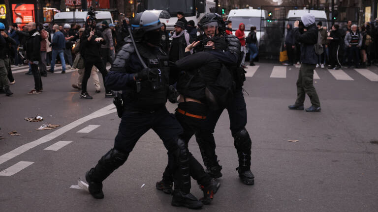 French Police officers clash with a protester (C) during a demonstration, a week after the government pushed a pensions reform through parliament without a vote, using the article 49.3 of the constitution, in Paris on March 23, 2023. - French unions on March 23, 2023, staged a new day of disruption against President Emmanuel Macron's pension reform after he defiantly vowed to implement the change, with refineries at a standstill and mass transport cancellations. (Photo by Thomas SAMSON / AFP)