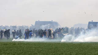 Protesters, surrounded by tear gas, clash with riot mobile gendarmes during a demonstration called by the collective 