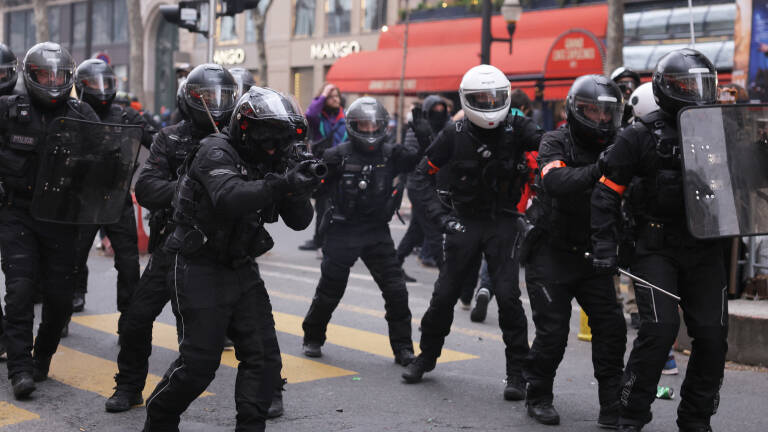 French police officers of the Repression of Violent Action Motorised Brigade (Brav-M or Brigade de repression de l'action violente motorisee) operate during a demonstration, including one (4thL) aiming with a rubber defensive bullet launcher (LBD), a week after the government pushed a pensions reform through parliament without a vote, using the article 49.3 of the constitution, in Paris on March 23, 2023. - French unions on March 23, 2023, staged a new day of disruption against President Emmanuel Macron's pension reform after he defiantly vowed to implement the change, with refineries at a standstill and mass transport cancellations. (Photo by Thomas SAMSON / AFP)