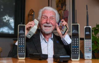 Engineer Martin Cooper holds in his right hand a contemporary copy of the original cell phone he used to make the first cell phone call on April 3, 1973, in Del Mar, California on March 20, 2023. - The problem with mobile phones is that people look at them too much. At least, that's according to the man who invented them 50 years ago. Martin Cooper, an American engineer dubbed the 