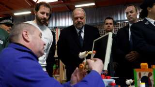 French Justice Minister Eric Dupond-Moretti (C) speaks with an inmate displaying his craftsmanship during a visit to a jail in Bois d'Arcy, south-west of Paris on April 4, 2023, highlighting the work of prisoners in the institution and in the prescence of several heads of commercial companies. (Photo by Geoffroy Van der Hasselt / AFP) (Photo by GEOFFROY VAN DER HASSELT/AFP via Getty Images)