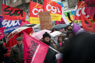 Protesters hold union flags and a placard with a play on words using French Prime Minister Elisabeth Borne's surname to read 