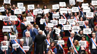 Members of National Assembly parliamentary group La France Insoumise (LFI) and left-wing coalition NUPES (New People's Ecologic and Social Union) hold signs reading 