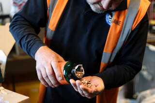 A Belgian customs officer opens a bottle that contains ecstasy pills as he controls packages at Brussels Airport in Zaventem on April 6, 2023. - Belgian bunnies will be an Easter treat for kids around the world this weekend, but not all are moulded from the country's renowned chocolate. A batch of rabbits seized this week by veteran customs officer Pol Meuleneire was crafted from a solid lump of MDMA, the raw material for pills of the rave drug ecstasy. (Photo by Kenzo TRIBOUILLARD / AFP)