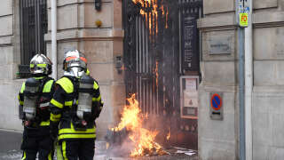 Firefighters work to extinguish a fire on the facade of a Banque de France building during the 11th day of demonstration against the government-pushed pensions reform that went through parliament without a vote, using the article 49.3 of the constitution, in Nancy, northeastern France on April 6, 2023. - France on April 6, 2023, braced for another day of protests and strikes to denounce French President's pension reform one day after talks between the government and unions ended in deadlock. (Photo by Jean-Christophe Verhaegen / AFP)