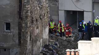 Firefighters and members of the emergency services stand among the rubble at 'rue Tivoli' a day after a building collapsed in the street, in Marseille, southern France, on April 10, 2023. - An apartment building collapsed in an apparent explosion on April 9, 2023 in the French Mediterranean city of Marseille, injuring five people, with authorities warning up to 10 victims could be under the burning rubble. (Photo by NICOLAS TUCAT / AFP)