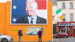 (FILES) In this file photo taken on October 07, 2020, pedestrians read an information board beneath a giant painting of US Presidential candidate Joe Biden, erected in his ancestral home of Ballina, north west Ireland. - When a British journalist once asked Joe Biden for an interview, the US president responded with a joke.
