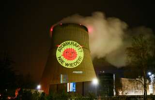 Activists of the nationwide anti-nuclear organisation 'ausgestrahlt' illuminate a cooling tower of the nuclear power plant Emsland run by German energy company RWE with the slogan 'Nuclear energy - never again' in Lingen, western Germany on April 10, 2023. - Germany will shut down its three remaining nuclear plants on April 15, betting that it can fulfil its green ambitions without atomic power despite the energy crisis caused by the Ukraine war. The cloud of white steam that has risen since 1989 over the river in Neckarwestheim, near Stuttgart, will soon be a distant memory, as will the Isar 2 complex in Bavaria and the Emsland plant in the north. Following the shutdown of the Emsland nuclear power plant, operator RWE expects the initial decommissioning phase, including post-operation, to last 14 years. (Photo by Ina FASSBENDER / AFP)