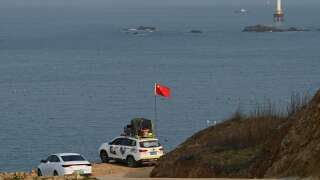 A man sets up a Chinese flag on his car as he prepares to look at the view of the Taiwan Strait, towards the zone where China said it would conduct live fire exercises northeast of Pingtan island, the closest point in China to Taiwan, in China’s southeast Fujian province on April 10, 2023. (Photo by GREG BAKER / AFP)