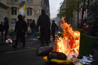 Protestors stand near garbage bins set on fire demonstration after the French constitutional court approved the key elements of the controversial pension reform, in Paris on April 14, 2023. - The French constitutional court on April 14, 2023, approved the key elements of President Emmanuel Macron's controversial pension reform, while rejecting certain parts of the legislation. (Photo by JULIEN DE ROSA / AFP)