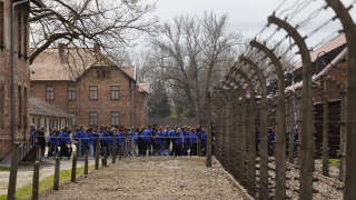 Participants walk past fences of the former Auschwitz-Birkenau camp during The March of the Living to honour the victims of the Holocaust, at the site of the Memorial and Museum Auschwitz-Birkenau in Oswiecim, Poland on April 28, 2022. (Photo by Wojtek Radwanski / AFP)