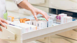 Une main de pharmacienne dans un tiroir de médicaments