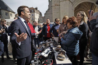 France's President Emmanuel Macron (L) speaks with local residents during a visit to a market in Dole, eastern France on April 27, 2023, before visiting Chateau de Joux for a ceremony. (Photo by Christophe PETIT TESSON / POOL / AFP)