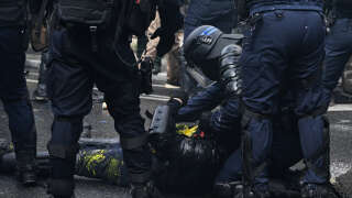 French riot police officers tend to an injured colleague on the ground during a demonstration on May Day (Labour Day), to mark the international day of the workers, more than a month after the government pushed an unpopular pensions reform act through parliament, in Paris, on May 1, 2023. - Opposition parties and trade unions have urged protesters to maintain their three-month campaign against the law that will hike the retirement age to 64 from 62. (Photo by Alain JOCARD / AFP)