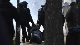 Police officers detain a protester during a demonstration on May Day (Labour Day), to mark the international day of the workers, more than a month after the government pushed an unpopular pensions reform act through parliament, in Paris, on May 1, 2023. - Opposition parties and trade unions have urged protesters to maintain their three-month campaign against the law that will hike the retirement age to 64 from 62. (Photo by JULIEN DE ROSA / AFP)