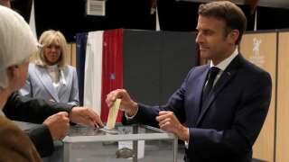France's President Emmanuel Macron casts his ballot next to his wife Brigitte Macron during the second stage of French parliamentary elections at a polling station in Le Touquet, northern France on June 19, 2022. (Photo by Michel Spingler / POOL / AFP)