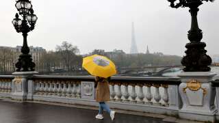A woman with an umbrella walks on Alexandre III bridge on a foggy day on March 30, 2022, in Paris. (Photo by Ludovic MARIN / AFP)
