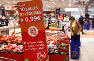 A customer looks at fruits et vegetables next to an information sign reading 