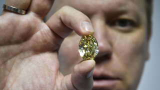 Russian Alrosa Diamond Deputy Director for sales Yevgeny Tsybukov shows a coloured, fancy brownish greenish yellow oval diamond, 50,21 carats, at Alrosa Diamond Cutting Division in Moscow on July 3, 2019. Russian Alrosa gets its diamonds in the permafrost abyssal holes dug with explosives in the permanently frozen ground of Yakutia, an isolated region in East Siberia, the home to the huge diamond deposits that ensure Russia's supremacy in world production. (Photo by Alexander NEMENOV / AFP)