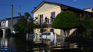 Residents stand on the balcony of their flooded property on May 21, 2023 in Conselice, near Ravenna, after deadly floodwaters hit the Emilia-Romagna region. More than 36,000 people have now been forced from their homes by deadly floods in northeast Italy, regional officials said, as rising waters swallowed more houses and fresh landslides isolated hamlets. Violent downpours earlier this week killed 14 people, transforming streets in the cities and towns of the Emilia Romagna region into rivers. (Photo by Andreas SOLARO / AFP)