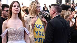 Ukrainian model Alina Baikova (C), wearing a t-shirt bearing the colours of the Ukrainian flag, talks with security as she arrives for the screening of the film 