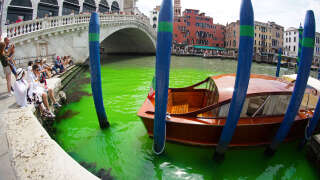 A photo taken and made available on May 28, 2023 by Italian news agency Ansa, shows fluorescent green waters below the Rialto Bridge in Venice's Grand Canal. The prefect called an urgent meeting on May 28 with the police to investigate the origin of the liquid, as gondoliers were getting lost in conjectures about the color's origin. (Photo by STRINGER / ANSA / AFP) / Italy OUT