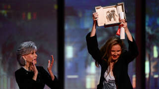 French director Justine Triet (R) celebrates on stage with US actress Jane Fonda after she won the Palme d'Or for the film 