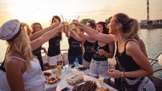 Cheerful bride and bridesmaids celebrating hen party on the boat.