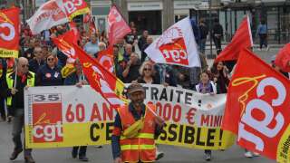 CGT unionists hold banners and flags during a demonstration against the unpopular pension reform, which the government pushed through parliament, in Rennes on May 23, 2023. French president has sparked the biggest demonstrations in a generation over reforms to the pension system, which include raising the retirement age to rise to 64 from 62 later this year. (Photo by JEAN-FRANCOIS MONIER / AFP)
