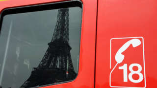 La tour Eiffel se reflète dans les vitres d'un camion de pompiers, le 10 août 2010 à Paris.  AFP PHOTO MIGUEL MEDINA (Photo by Miguel MEDINA / AFP)