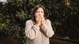 Une femme qui tient un mouchoir sur son nez souffrant d’allergies.