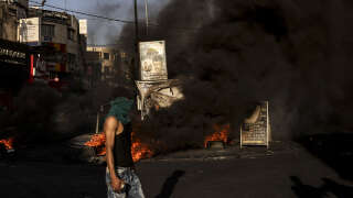 Un homme masqué marche près d’un feu lors d’affrontements avec l’armée israélienne dans la ville de Jénine, en Cisjordanie occupée, le 4 juillet 2023, lors d’une opération militaire en cours.