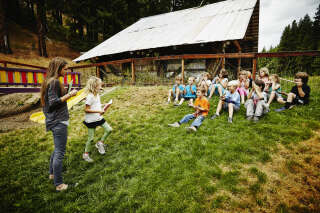 Camp counselor handing out awards to summer camp students outdoors in playground at the end of summer camp program